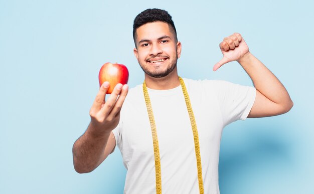 Expressão feliz jovem hispânico e segurando uma maçã. conceito de dieta