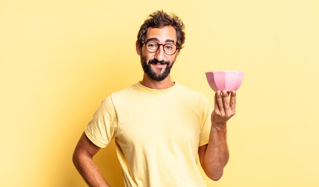 Expressivo louco sorrindo alegremente com uma mão no quadril e confiante e segurando um pote