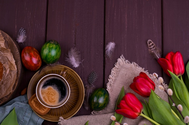 Expresso aromático fresco e brownie, sobre uma mesa de madeira. Café da manhã de primavera, flores, tulipas, bolos e café. Vista do topo. Espaço livre para texto