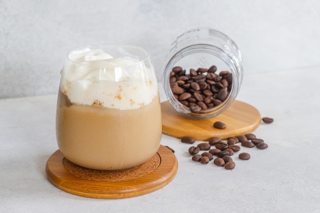 Expresso frÃo con espuma de leche frÃa con cafÃ © molido marrÃ³n y granos de cafÃ © espolvoreado em uma mesa branca