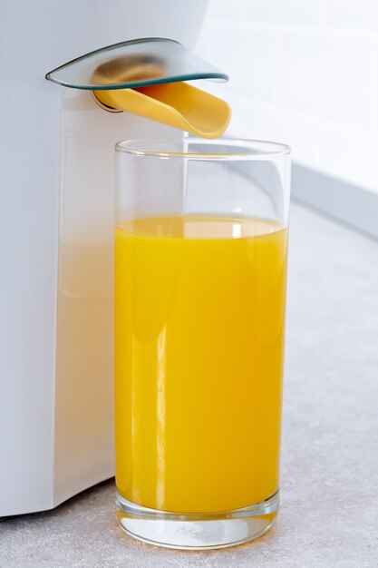 Exprimidor con un vaso de jugo de naranja natural en una cocina moderna.