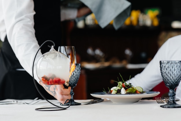Una exquisita ensalada de mariscos, atún y caviar negro en una hermosa quema con fuego que se sirve en la mesa del restaurante. Exquisitos manjares de la alta cocina en primer plano.
