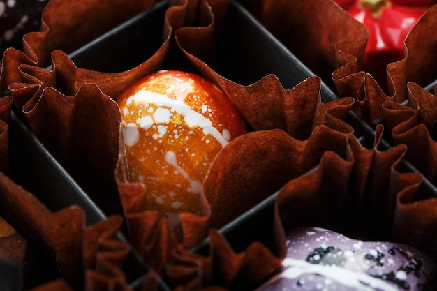 Exquisitos dulces de chocolate hechos a mano están pintados con patrones de primer plano de estrellas galácticas
