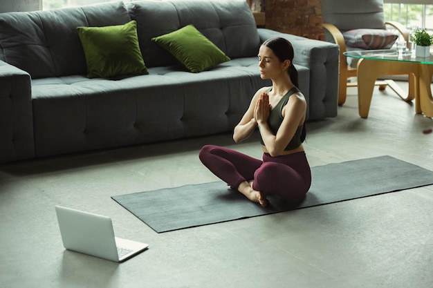 Extensión. Deportiva hermosa joven practicando asanas de yoga como profesional en casa.