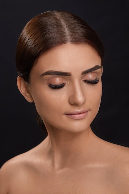 Extensiones de pestañas. Pestañas postizas. Primer plano de la hermosa modelo de mujer joven con piel suave y lisa y maquillaje facial profesional. Retrato de chica sexy con pestañas postizas largas y maquillaje perfecto.