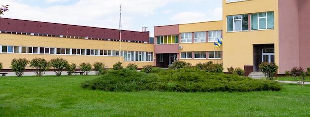 Exterior de la arquitectura del edificio escolar alrededor del patio con espacio verde, campus.