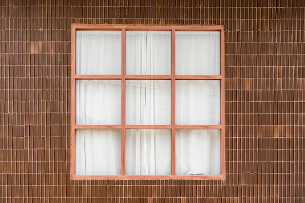 Exterior de baldosas de arcilla de pared y ventana de madera con cortina blanca de casa tropical