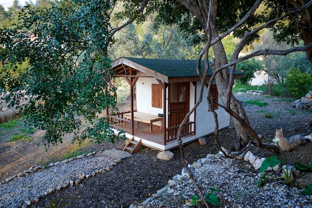 El exterior de un bungalow de estilo mediterráneo se baña en el brillo de ensueño de la puesta de sol Las plantas exuberantes crecen en su patio trasero dándole una sensación acogedora