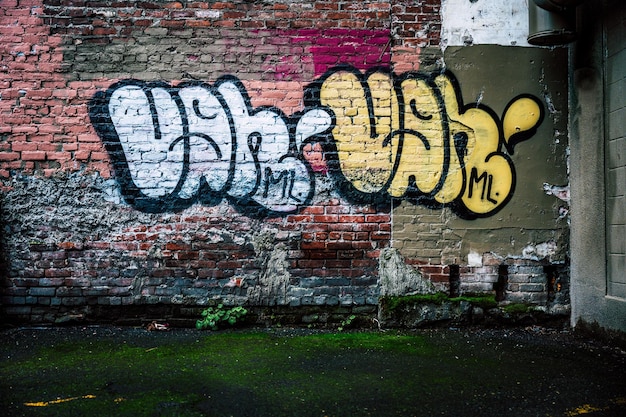 Exterior de edifício velho com parede de tijolos com inscrição de graffiti na rua da cidade Foto