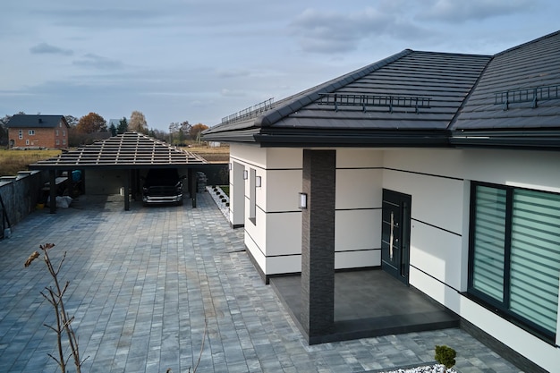 Exterior de uma casa moderna e confortável, com uma porta elegante, um pátio pavimentado e janelas fechadas