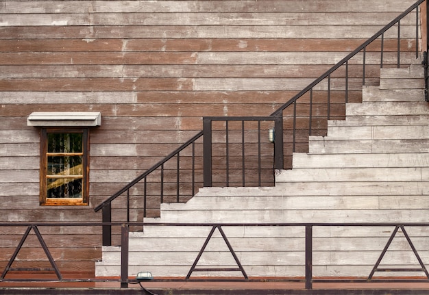 Exterior del edificio de madera con ventana y escaleras.