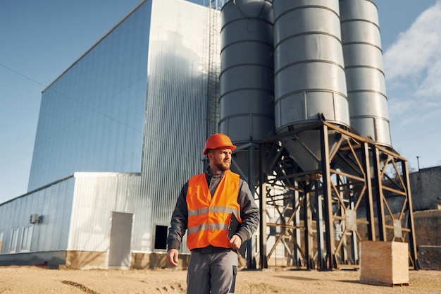 Exterior del edificio Trabajador de la construcción en uniforme está al aire libre cerca de la fábrica