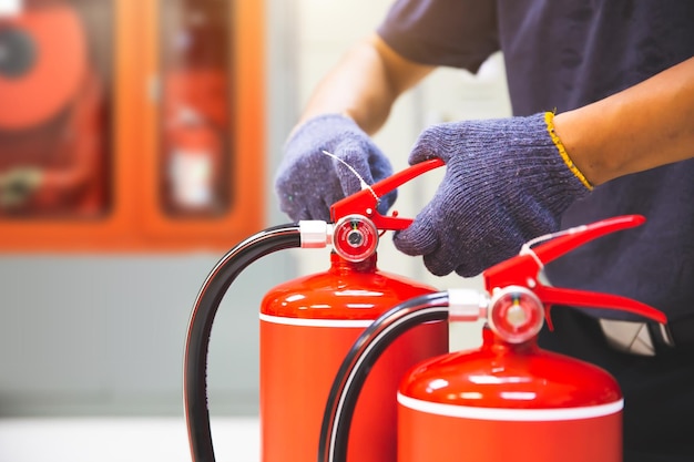 Extintor de incêndio tem inspeção de mão de engenheiro verificando medidores de pressão para preparar equipamentos de incêndio para proteção e prevenção em caso de emergência e segurança ou resgate e conceito de treinamento do sistema de alarme