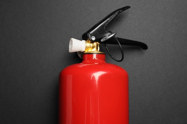 Un extintor de fuego rojo en fondo gris oscuro vista superior