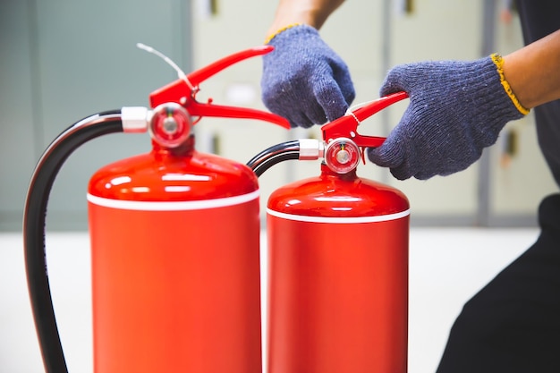 Foto el extintor de incendios tiene el ingeniero de mano tirar del alfiler de seguridad en el mango para comprobar