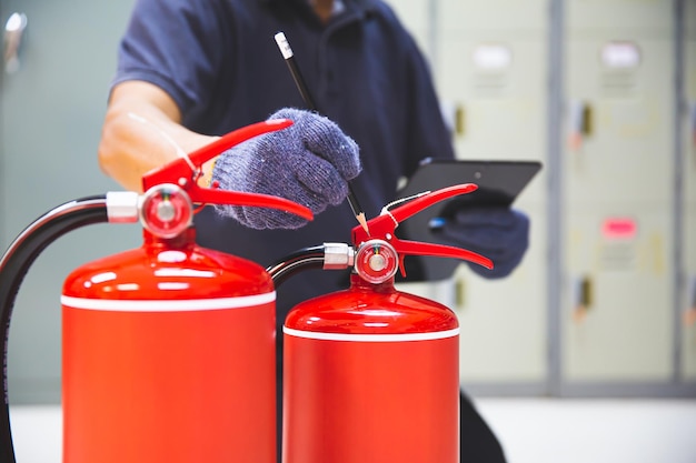 Foto el extintor de incendios tiene inspección manual de ingenieros que verifica los manómetros para preparar el equipo contra incendios para protección y prevención en caso de emergencia y concepto de capacitación en sistemas de seguridad o rescate y alarma