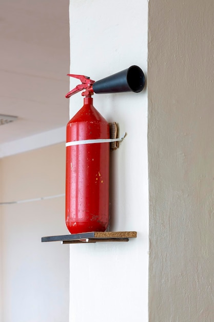 Extintor portátil de mano montado en la pared dentro de la habitación