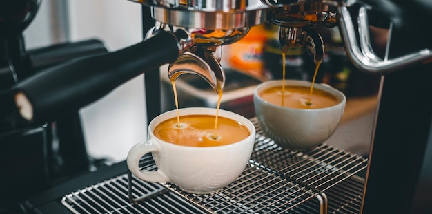 Foto extração de café da máquina de café com um porta-filtro despejando café em uma xícara.