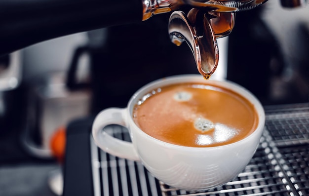 Extracción de café de la máquina de café con un portafiltro vertiendo café en una taza.Espresso