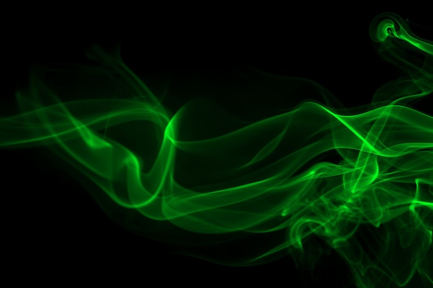 Extracto verde del humo en fondo negro y concepto de la oscuridad