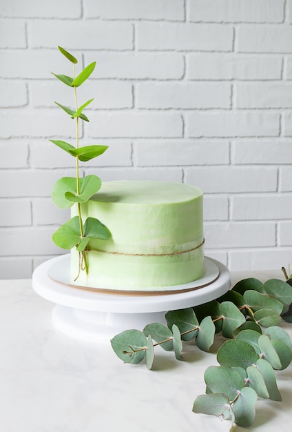 Extraordinário bolo verde festivo decorado com um ramo de eucalipto. Copie o espaço.