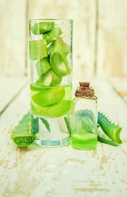 Extrato de Aloe Vera em uma pequena garrafa e peças em cima da mesa. Foco seletivo.