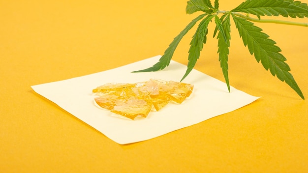 Extrato forte de cera de cannabis ouro com alto thc em fundo amarelo close-up.