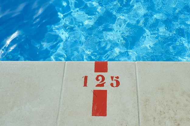 Foto extremidade profunda de uma piscina com sinal marcando profundidade piscina externa na estação quente