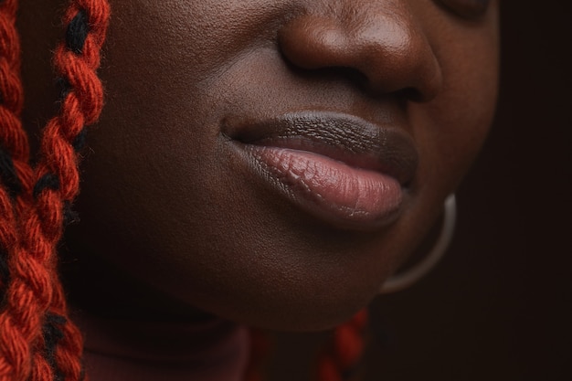 Extremo cerca de la joven mujer afroamericana con cabello trenzado se centran en los labios y rasgos faciales naturales y regordetes