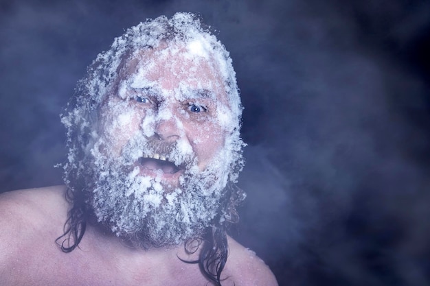 Extremo ruso un hombre desnudo en la nieve con barba congelada y cabello en las nubes de vapor