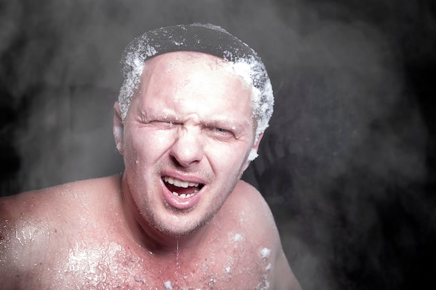 Extremo russo um homem nu na neve com barba congelada e cabelo nas nuvens de vapor