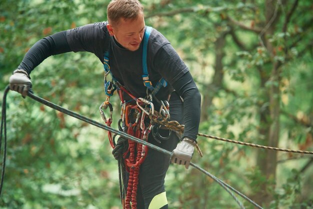 Foto extremsport in der höhe der mensch klettert im wald mit sicherheitsgeräten