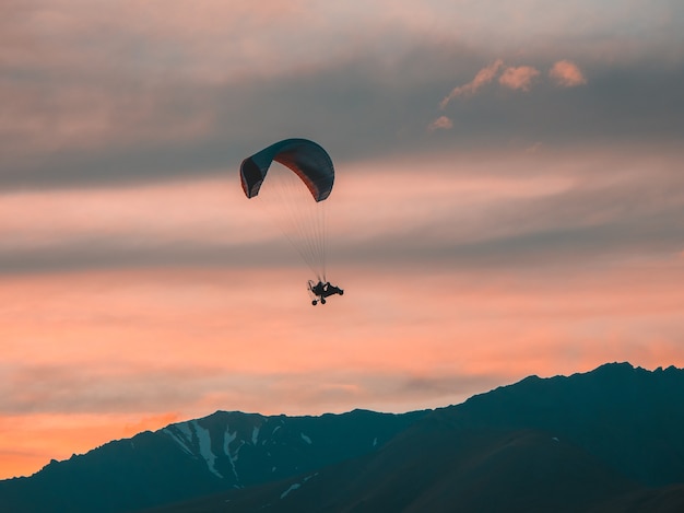 Extremsportarten. Angetriebener Fallschirm über den Bergen bei Sonnenuntergang.