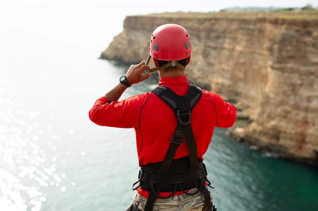 Extremsportler befestigt einen Schutzhelm am Rand einer Klippe, bevor er Seilspringen springt