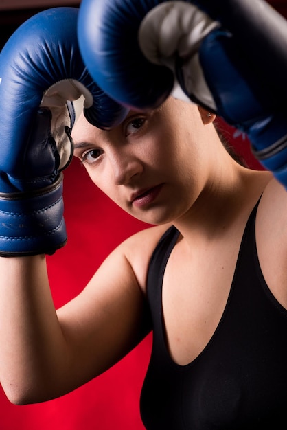 Extremsportlerin mit blauen Boxhandschuhen auf dunkelrotem Hintergrund