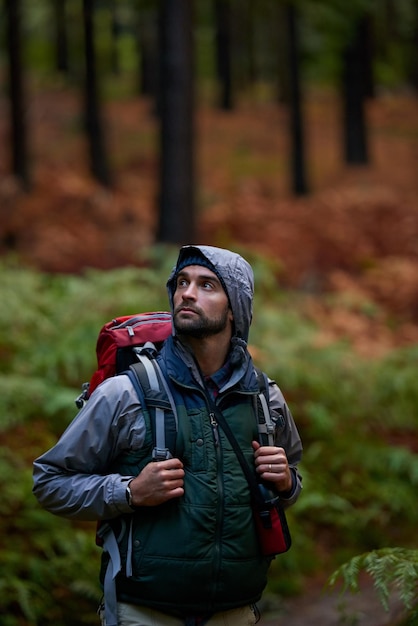 Exuberante desierto natural Retrato de un joven que lleva una mochila mientras camina por el bosque