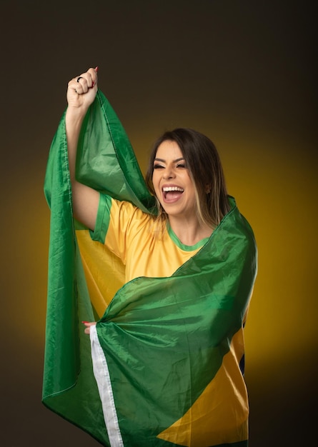 Fã brasileira Fã brasileira comemorando no futebol ou partida de futebol em fundo amarelo cores do Brasil