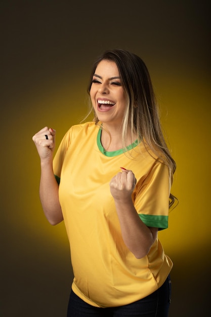 Fã brasileira Fã brasileira comemorando no futebol ou partida de futebol em fundo amarelo cores do Brasil