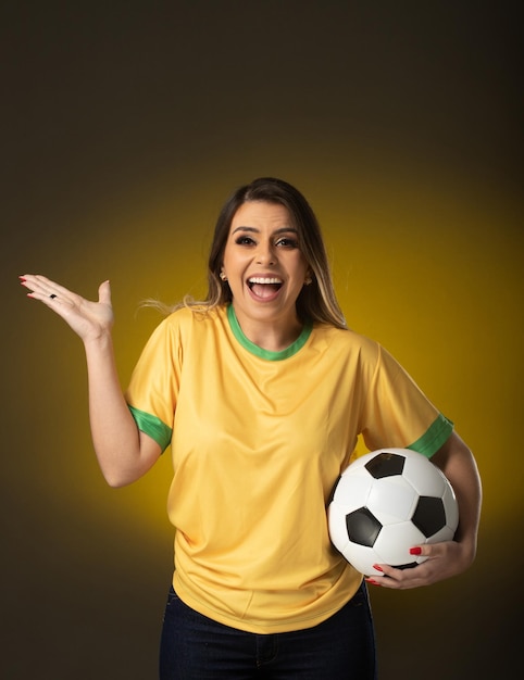 Fã brasileira Fã brasileira comemorando no futebol ou partida de futebol em fundo amarelo cores do Brasil
