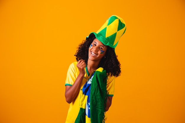 Fã brasileira. fã brasileiro comemorando futebol ou jogo de futebol em fundo amarelo. cores do brasil.