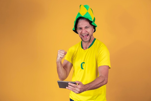 Fã brasileiro de meia idade assistindo jogo pelo smartphone