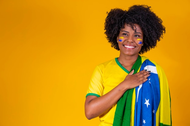 Fã brasileiro vestindo bandeira brasileira em um retrato fã brasileiro comemorando jogo de futebol ou futebol em fundo amarelo cores da copa do mundo do brasil