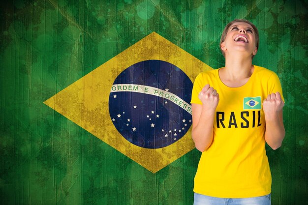 Foto fã de futebol animado em camiseta do brasil contra a bandeira do brasil em efeito grunge