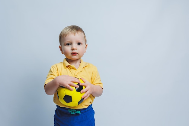 Fã de futebol de 34 anos de idade em uma camiseta amarela com uma bola nas mãos segurando uma bola de futebol nas mãos isoladas em um fundo branco O conceito de recreação familiar esportiva