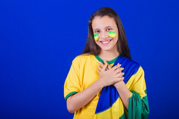 Fã de futebol jovem do Brasil vestido com bandeira cantando o hino nacional Gratidão