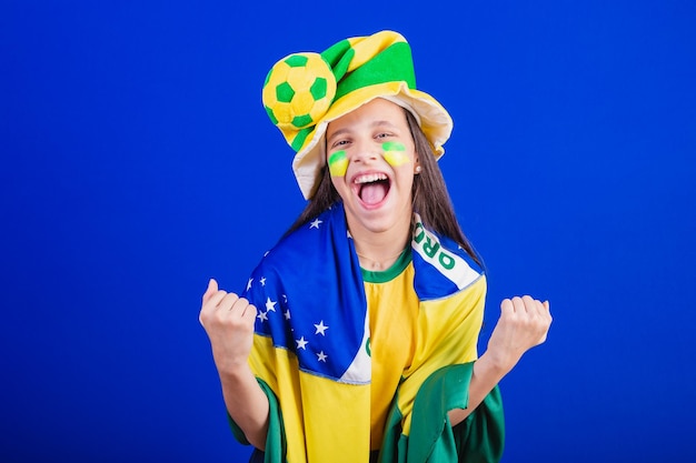 Fã de futebol jovem do brasil vestido de chapéu e bandeira gritando gol