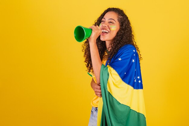 Foto fã de futebol jovem negra brasileira gritando através de alto-falante foto publicitária