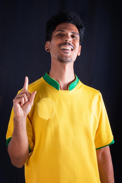 Fã de jogador negro de futebol brasileiro com camisa amarela comemorando