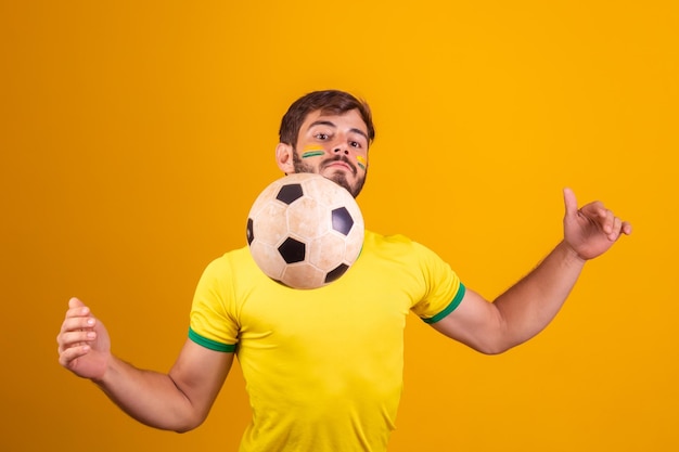 Fã de jovem rapaz bonito do Brasil brincando com uma bola de futebol
