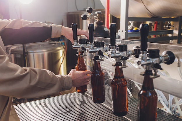 Fábrica de cervejaria derramando cerveja em garrafas de vidro nas linhas transportadoras. trabalho industrial, produção automatizada de alimentos e bebidas. trabalho tecnológico na fábrica.